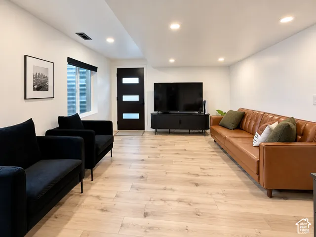 Recessed lighting, light wood-finish flooring, white walls, and a contemporary entry door with frosted glass panels