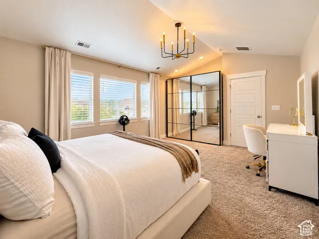 Vaulted ceiling with an attached chandelier, multiple windows with blinds, a mirrored closet, and plush carpet flooring