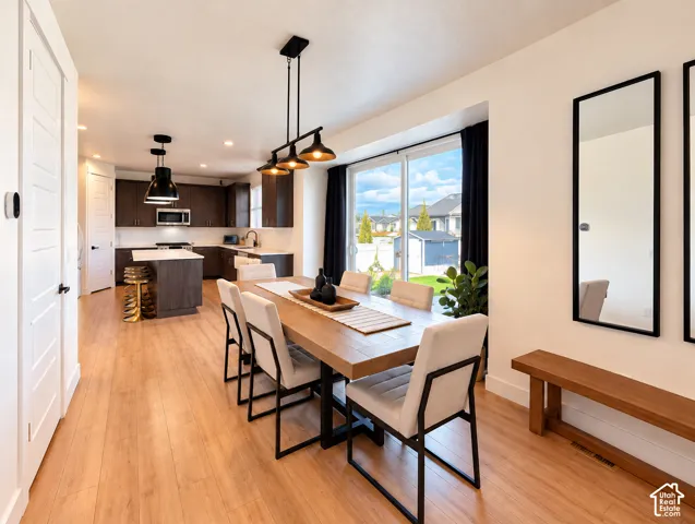 Open-concept living space with wood-finish flooring, a contemporary kitchen featuring a central island, and a dining area with a modern chandelier