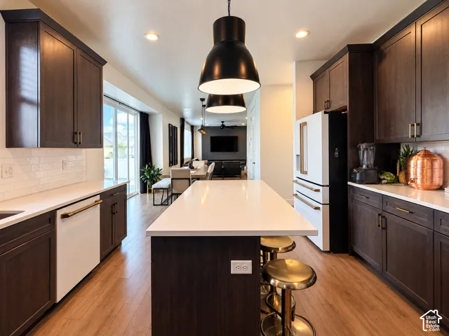 Kitchen featuring dark wood-finish cabinetry, white countertops, subway tile backsplash, and wood-finish flooring