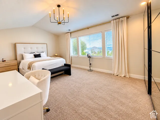 Vaulted ceilings with a modern black and brass chandelier, soft carpet flooring, and a bank of windows with horizontal blinds and drapery
