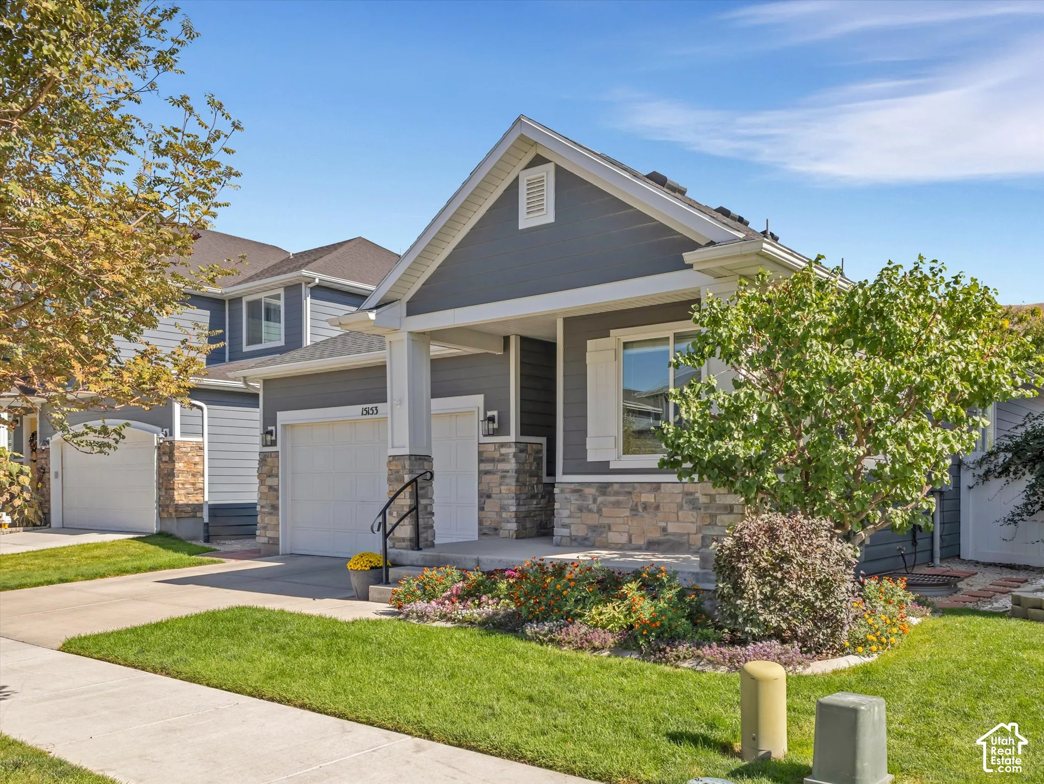 Exterior featuring a covered porch, stone veneer accents, and gray siding
