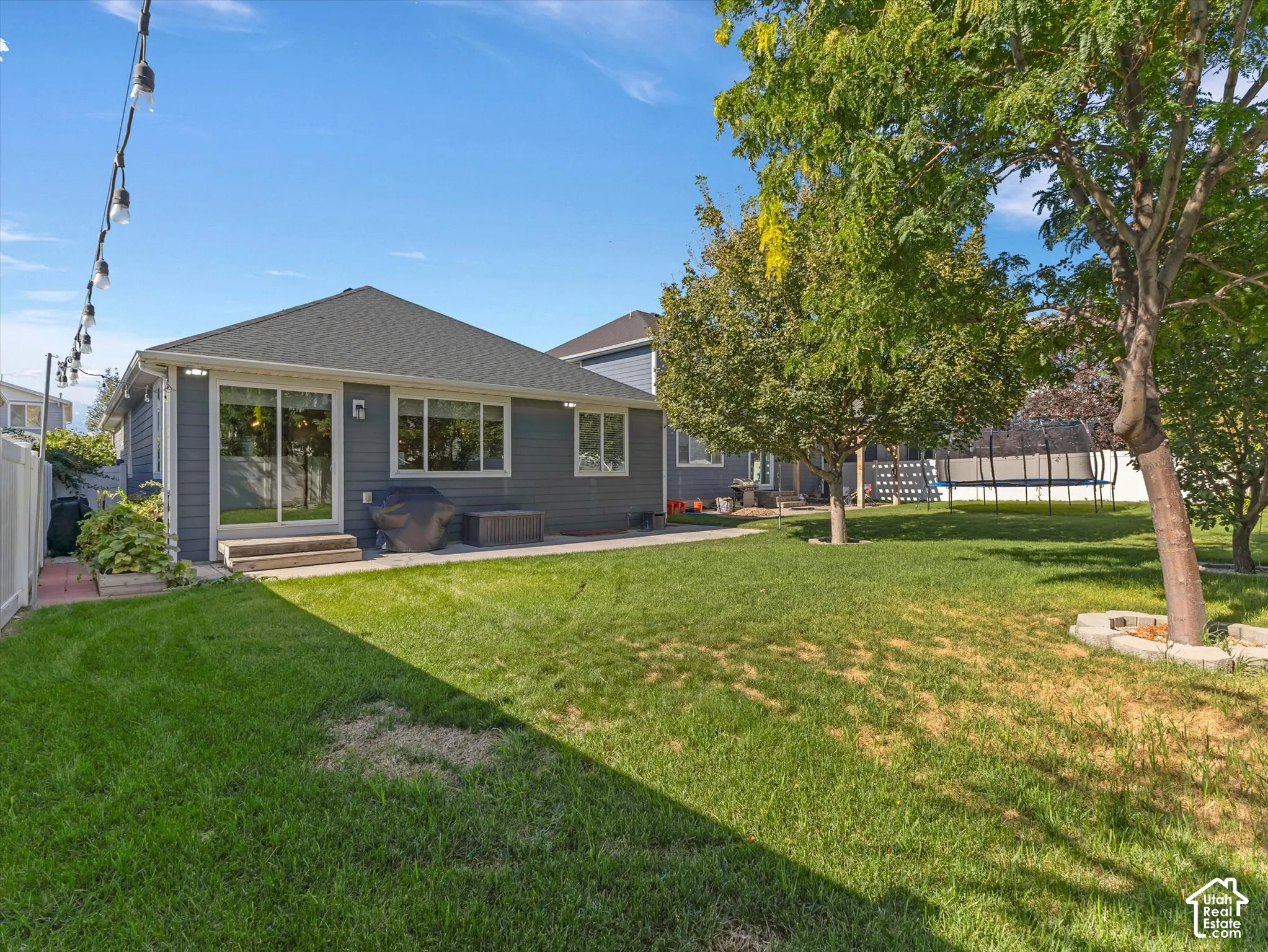 Expansive backyard featuring a manicured lawn, mature trees, and a privacy fence