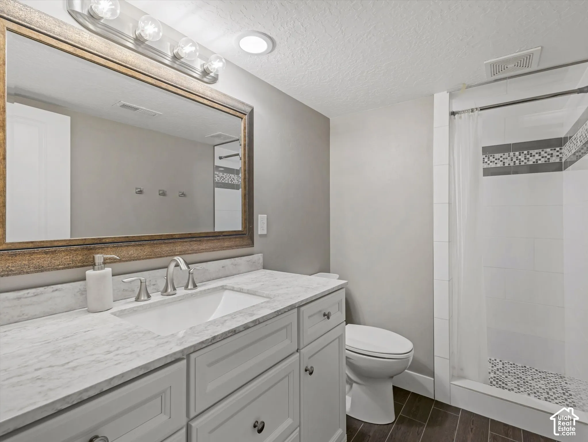 White vanity with a light-colored countertop, undermount sink, and brushed nickel faucet