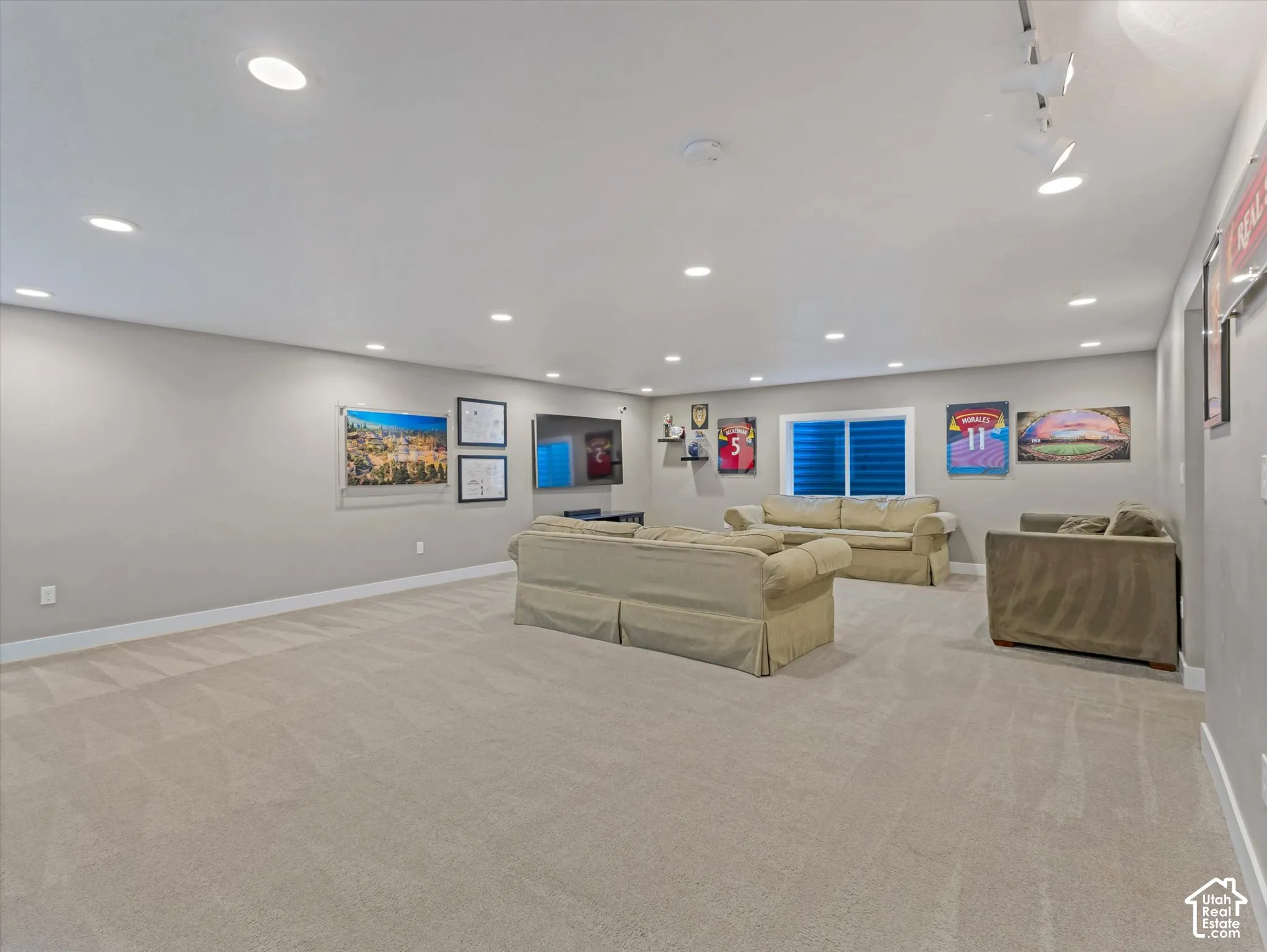 Expansive carpeted room with recessed lighting, a window with horizontal blinds, and track lighting