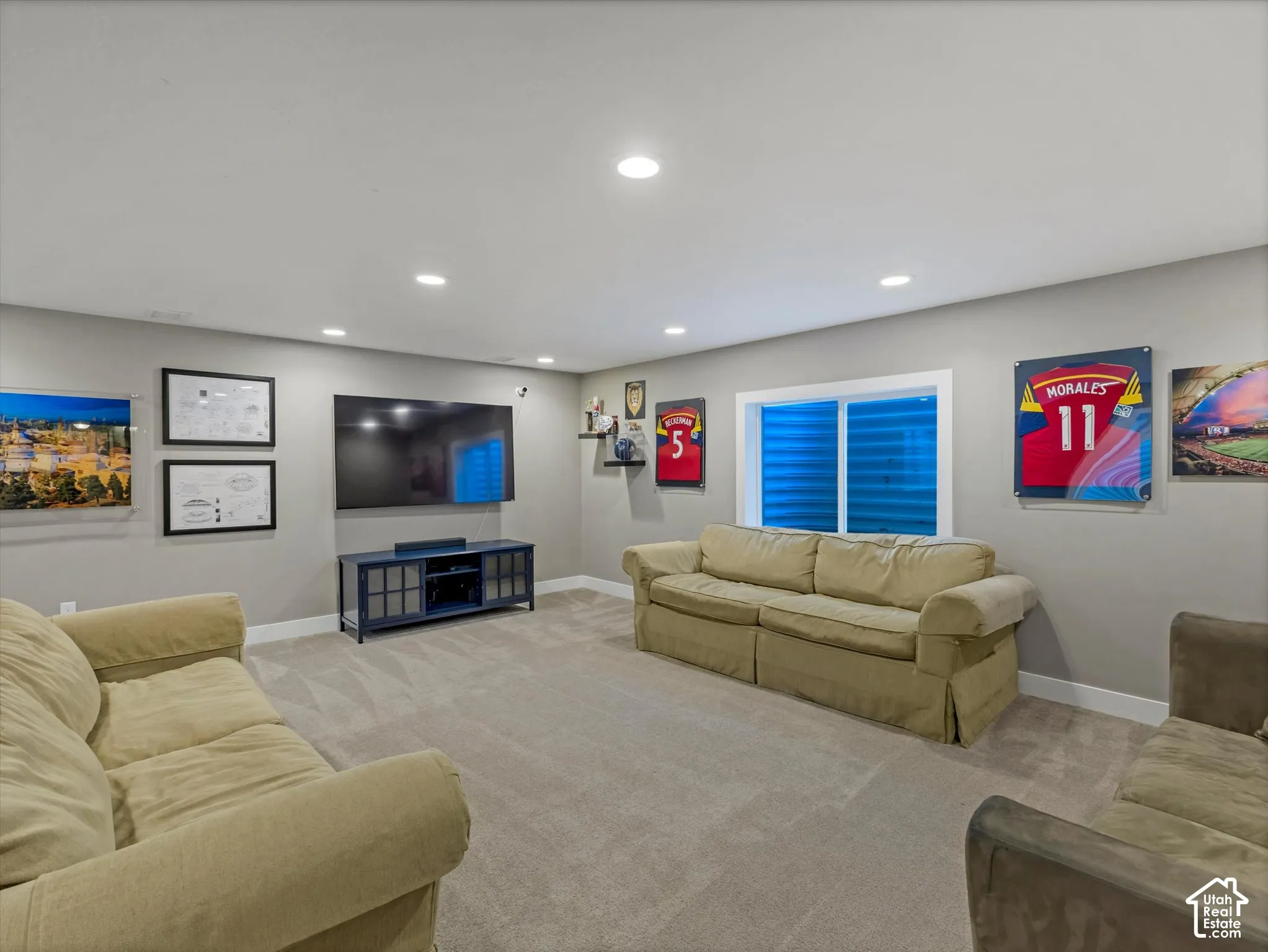 Carpeted floor, recessed ceiling lighting, light gray walls, and a built-in media console