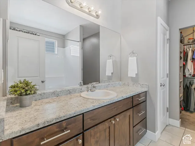 Extended single vanity with a speckled countertop, integrated sink, and dark wood-finish cabinetry