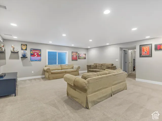 Recessed ceiling lighting, light gray wall tones, carpet flooring, and a single window with horizontal blinds