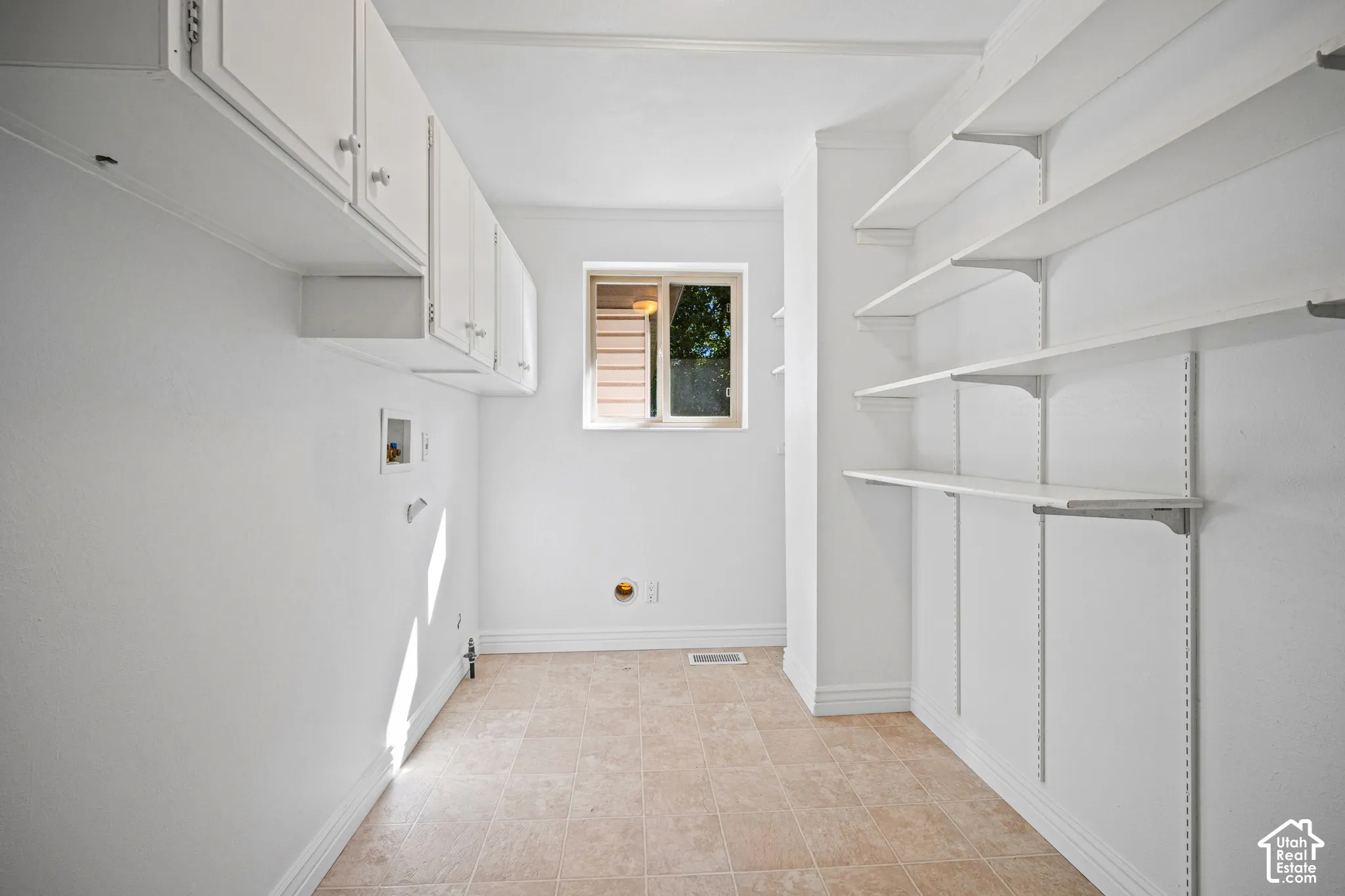 Upper cabinetry with white finish, adjustable shelving, and a window for natural light