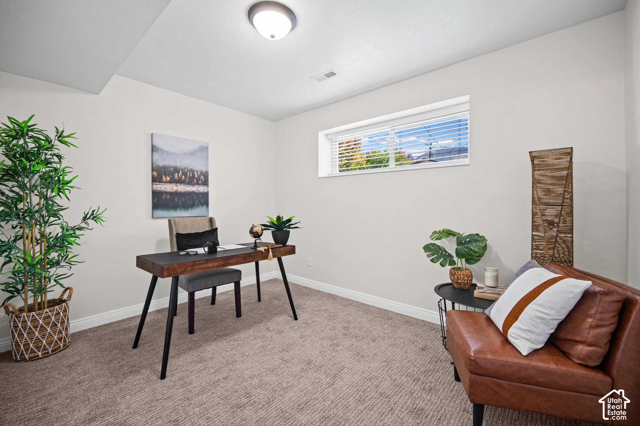 Dedicated home office featuring a mid-century modern wood desk with tapered legs, neutral carpeting, and abundant natural light from a transom window