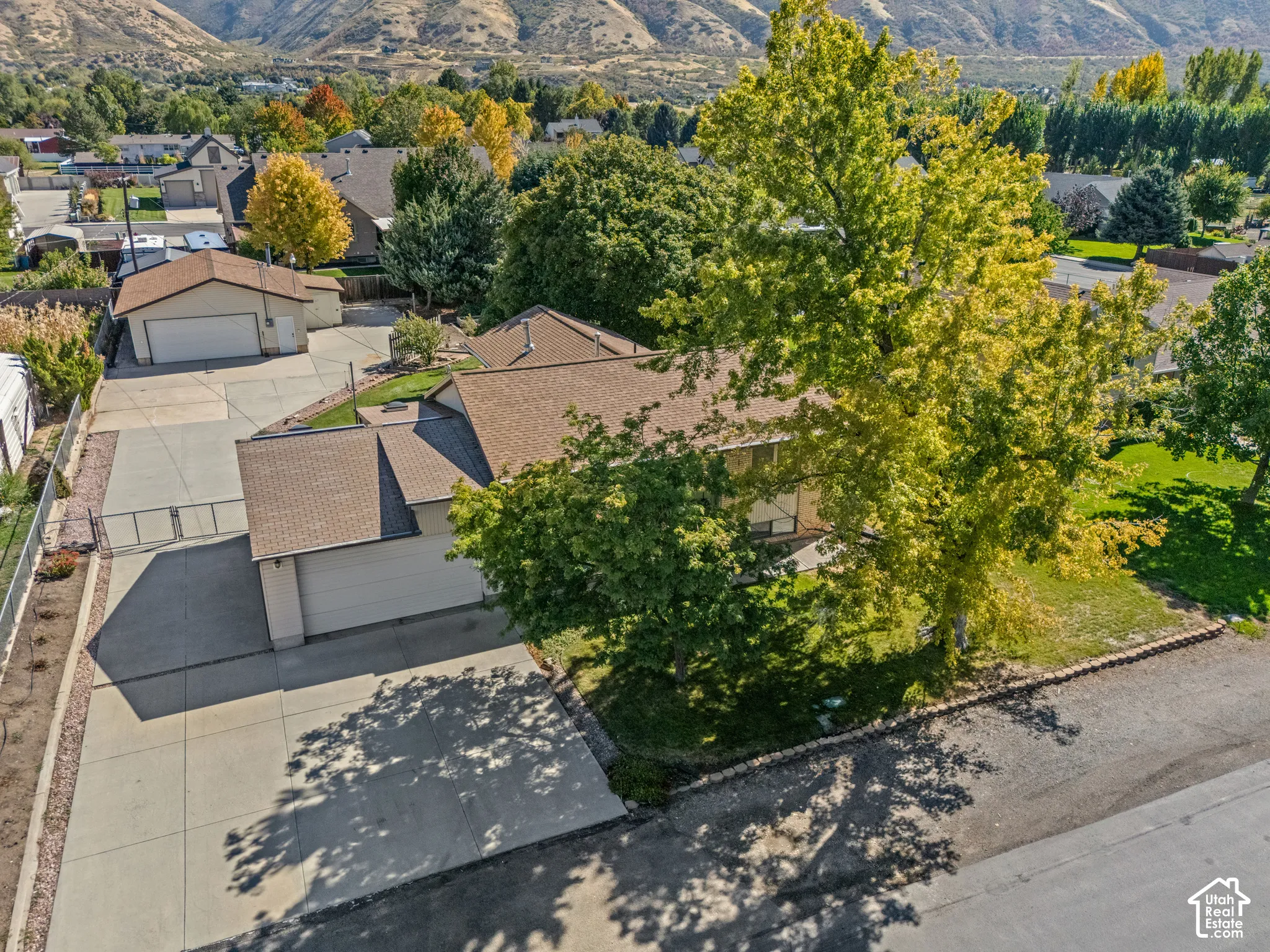 Expansive paved driveway, attached garage, detached garage, mature trees, and mountainous backdrop