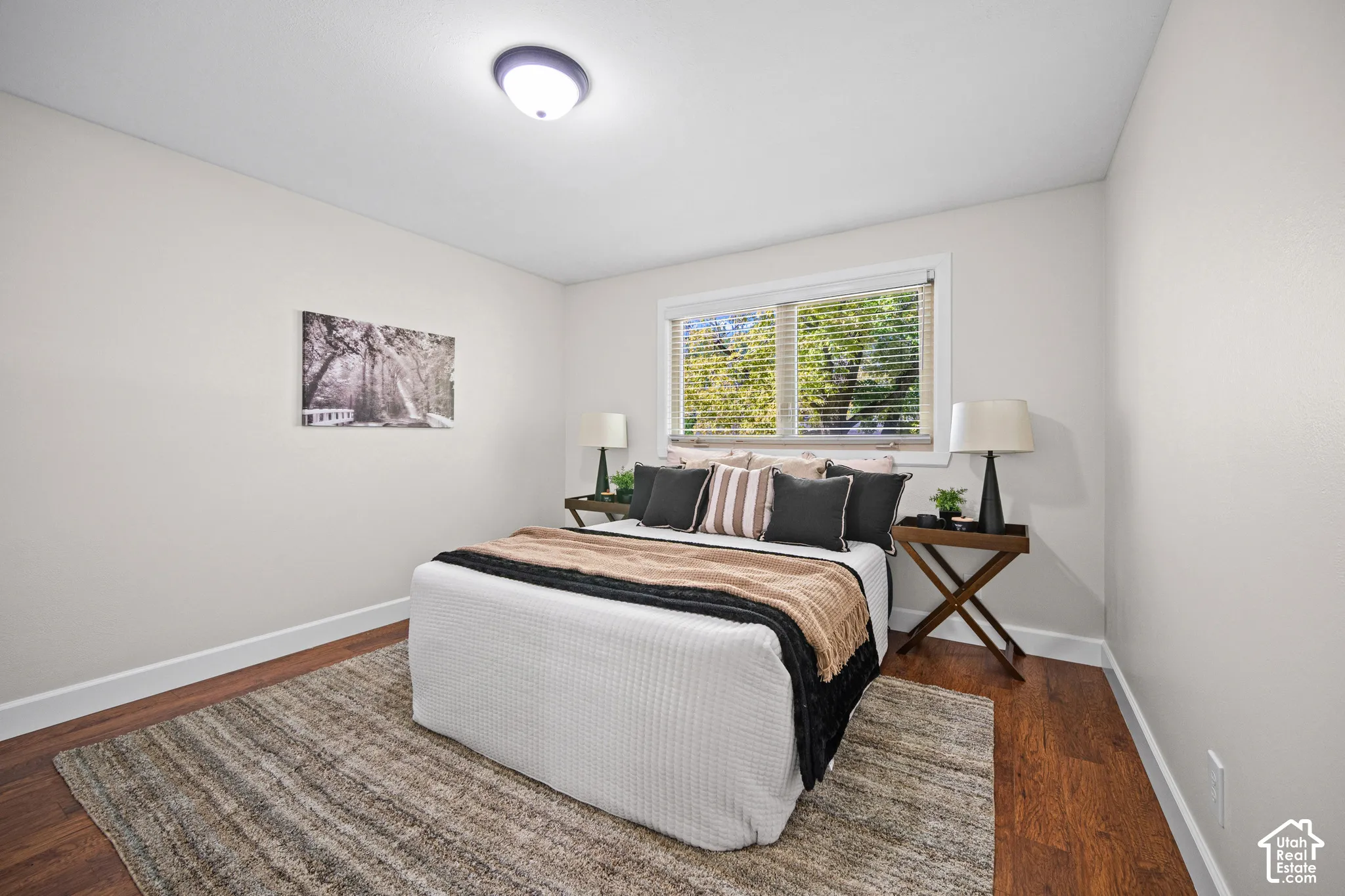 Bright interior with a flush mount ceiling light, wide window, wood-finish flooring, and white baseboards