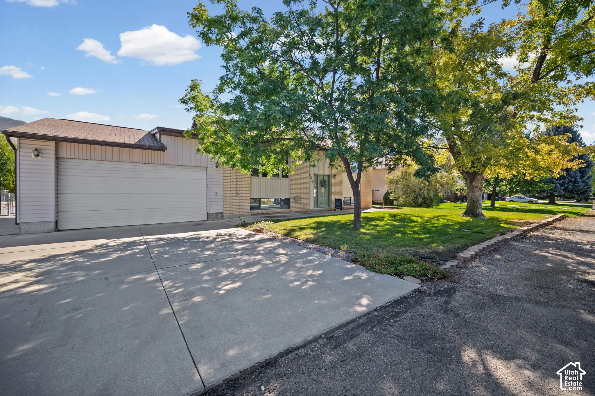 Welcoming driveway with concrete paving leading to an attached two-car garage featuring overhead doors
