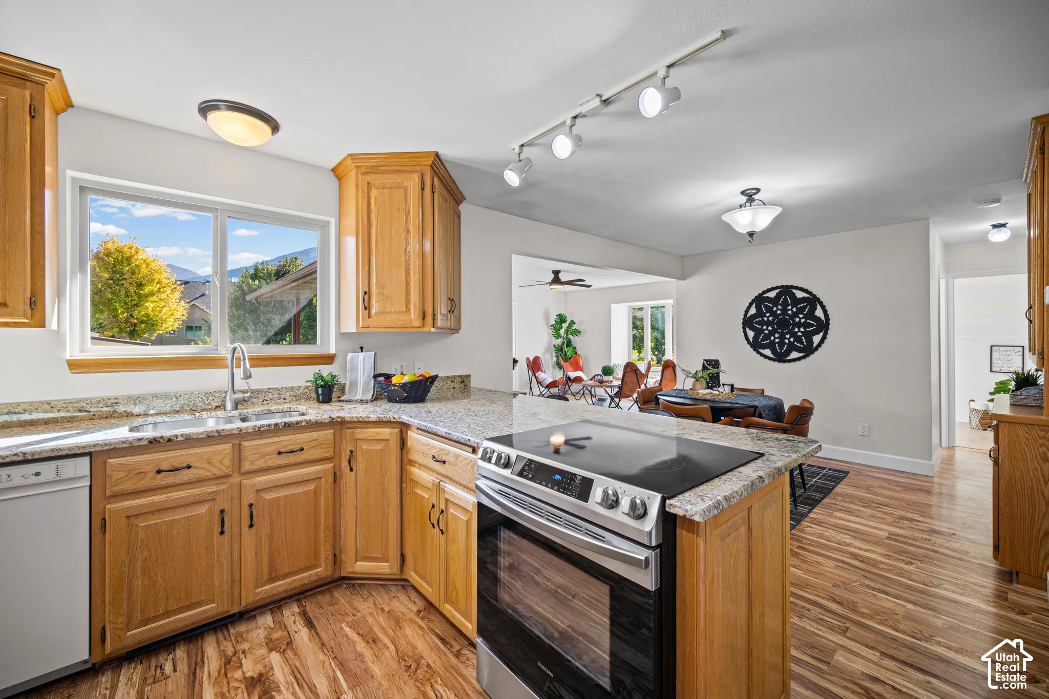 Kitchen featuring wood-finish flooring, light wood cabinetry, stone countertops, and a built-in range