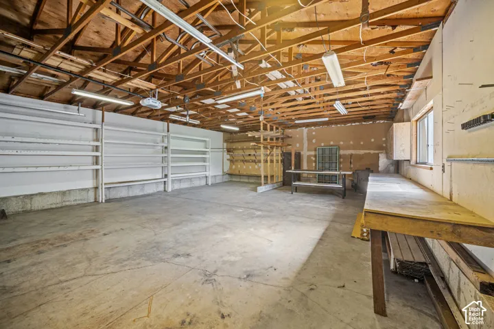 Concrete flooring, exposed wood beam ceiling, built-in shelving, workbenches, and window