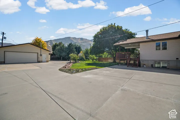 Expansive concrete driveway, detached garage with dual bay door, and a multi-level wood deck