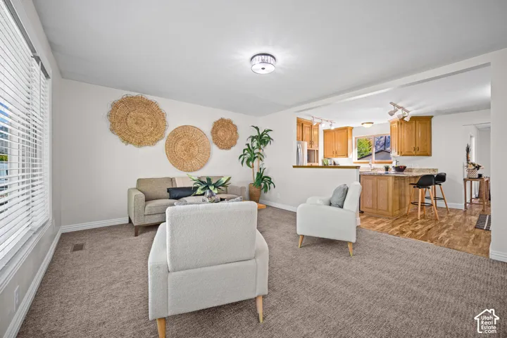 Open-concept living area featuring neutral-toned upholstered seating, woven wall accents, and abundant natural light from large windows