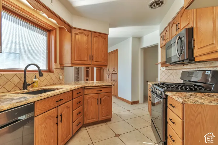Wood cabinetry with dark hardware, granite-style countertops, and a tiled backsplash