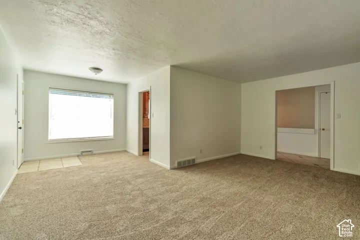 Expansive carpeted room with neutral wall tones and a wide window