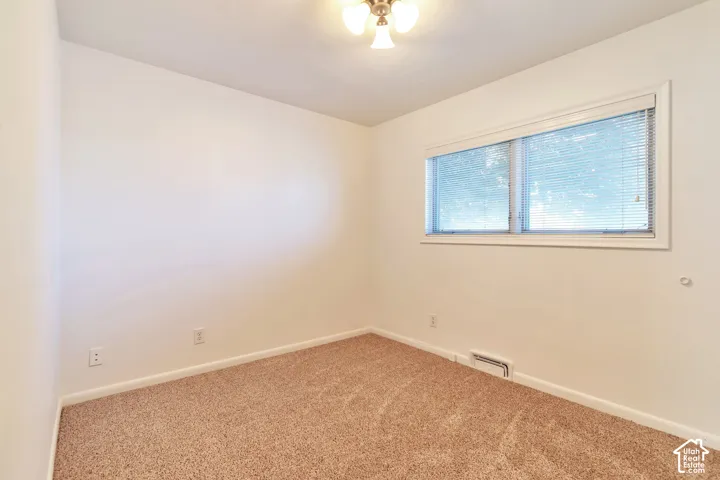 Neutral-toned carpet flooring, white walls, and a multi-pane window with horizontal blinds