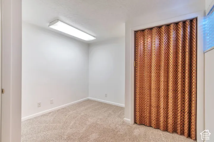 Recessed fluorescent lighting, textured carpet, white walls, and a patterned accordion door