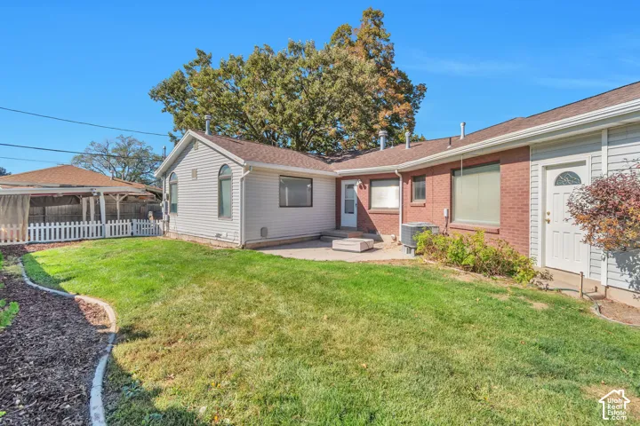 Expansive backyard featuring a manicured lawn, brick exterior, vinyl siding, and a concrete patio