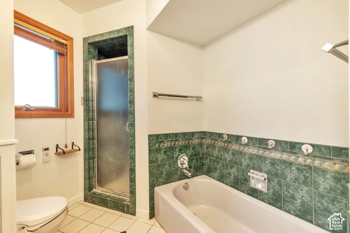 Tiled shower with frosted glass door, built-in bathtub with shower fixture, and green tiled wainscoting