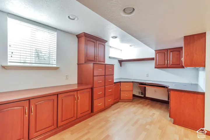 Built-in cabinetry with wood-finish doors and drawers, integrated desk area, overhead shelving, and recessed lighting