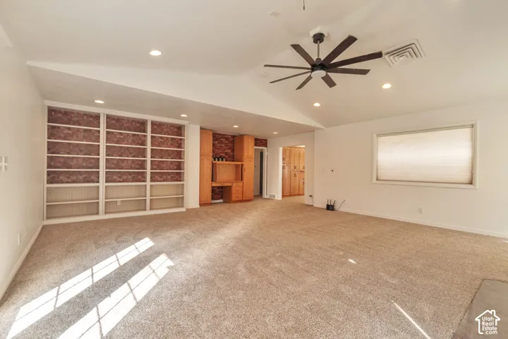 Spacious room featuring carpet flooring, built-in shelving, recessed lighting, a ceiling fan, and a built-in desk with cabinetry