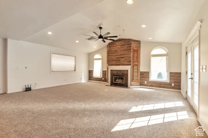 Spacious room featuring a corner fireplace with stone veneer, vaulted ceilings, and recessed lighting
