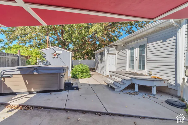 Rear patio featuring a hot tub, concrete paving, and a detached shed