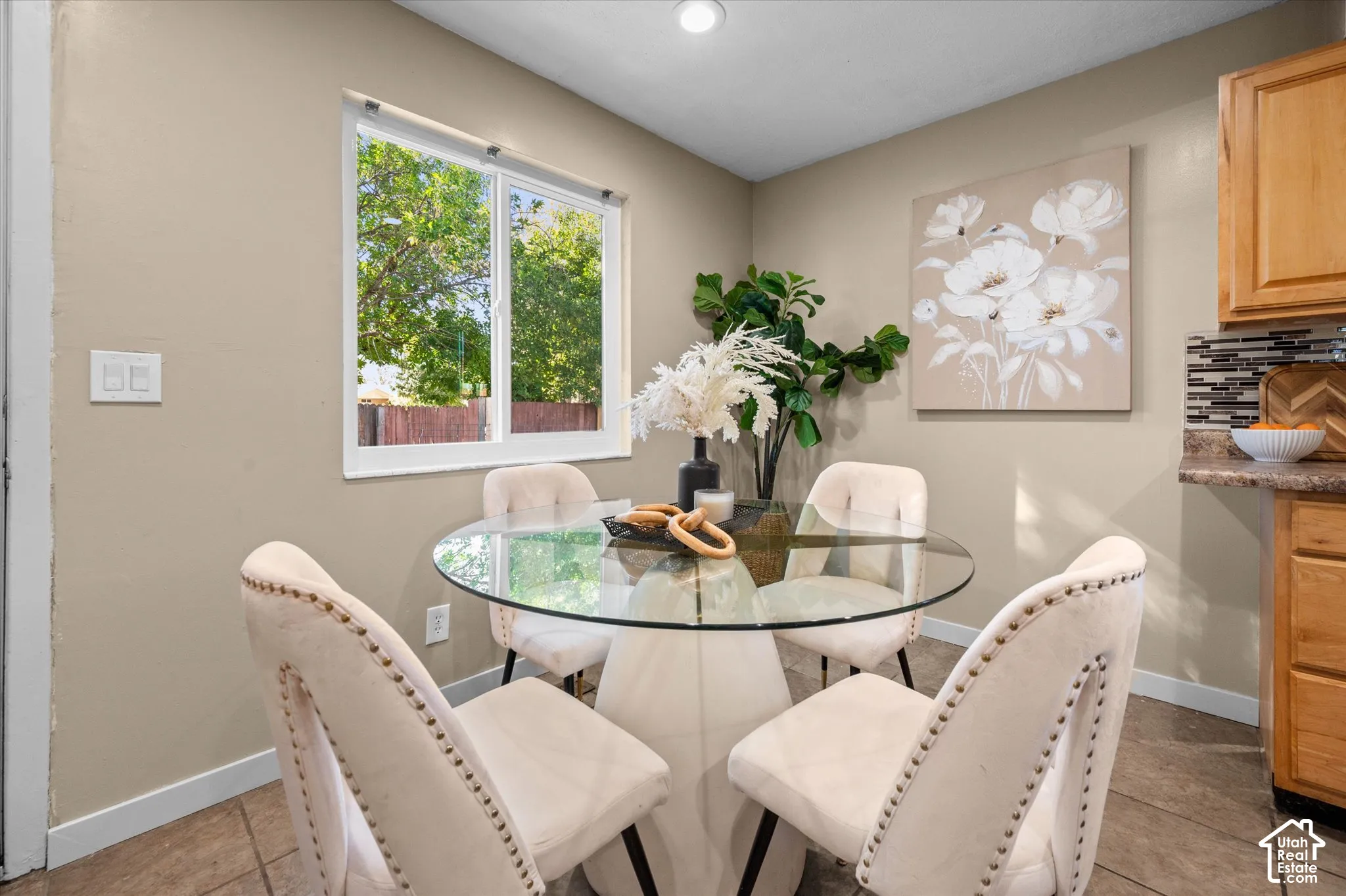 Recessed ceiling lighting, a window with white trim, tan painted walls, and wood-finish cabinetry