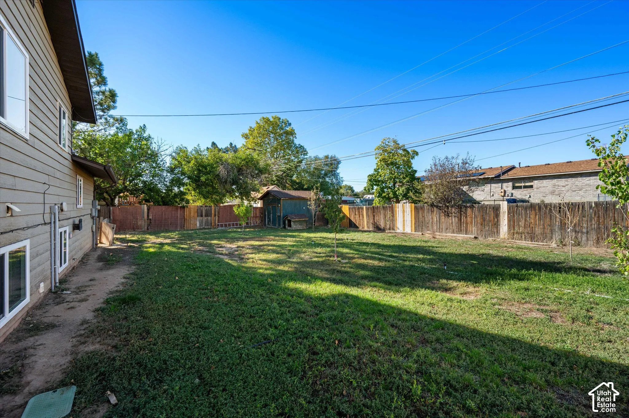 Expansive backyard featuring a mature lawn with established shade trees and wooden privacy fencing