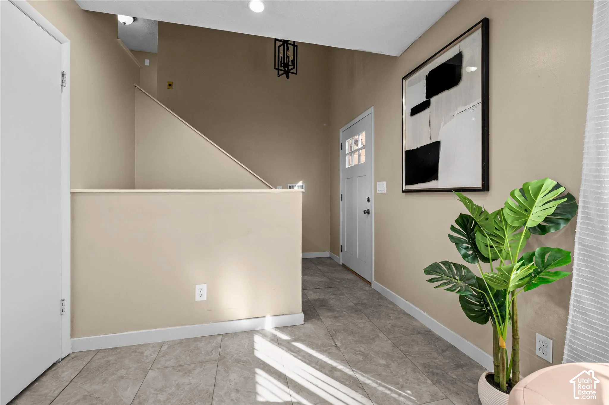 Modern entryway featuring neutral-toned walls, tile flooring, recessed ceiling lighting, and contemporary black-framed artwork
