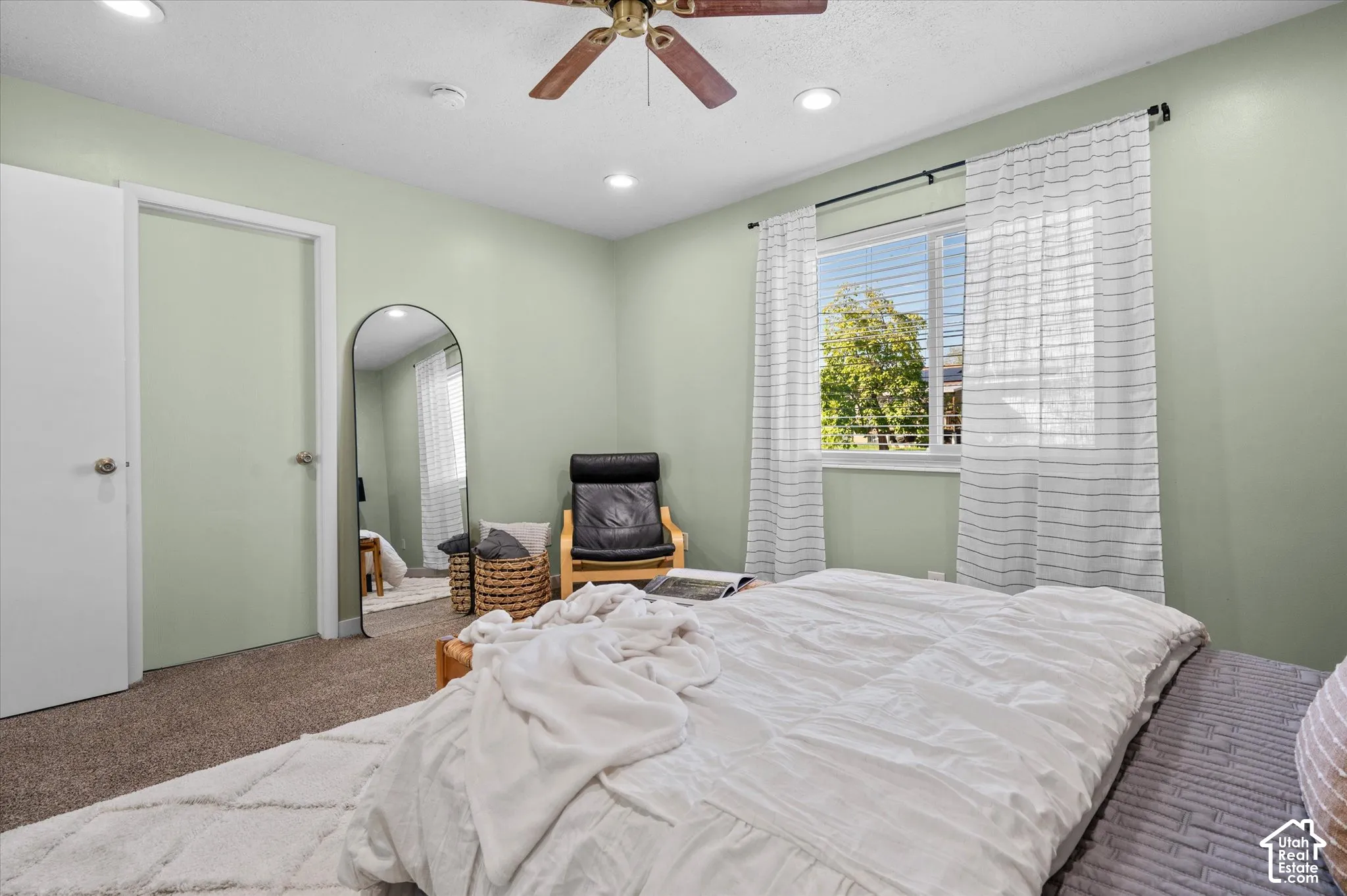 Bright secondary bedroom featuring soft sage-green walls, carpet flooring, and dual closets with white panel doors