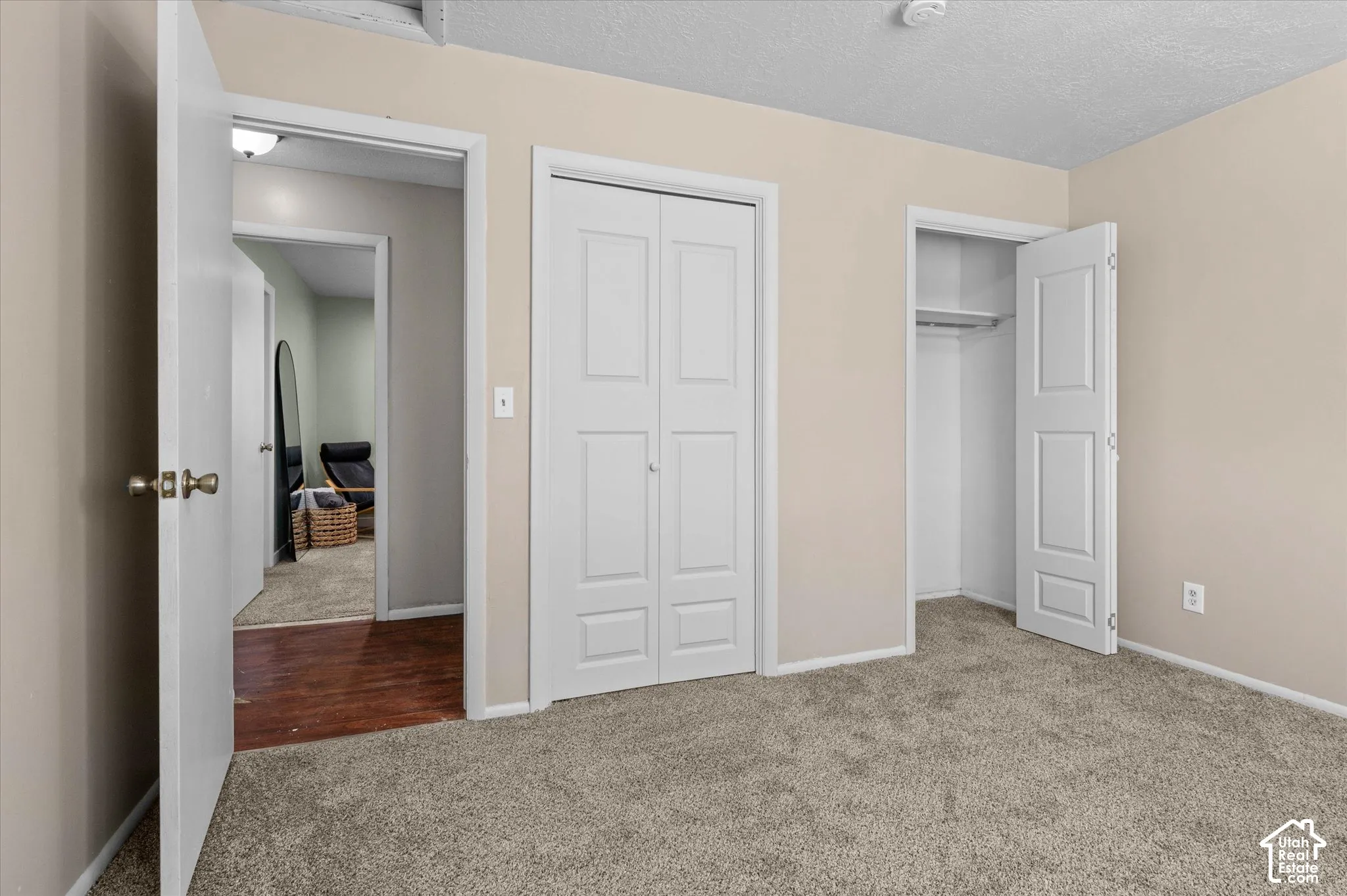 Textured carpet flooring, neutral painted walls, white trim, and a built-in closet with shelving