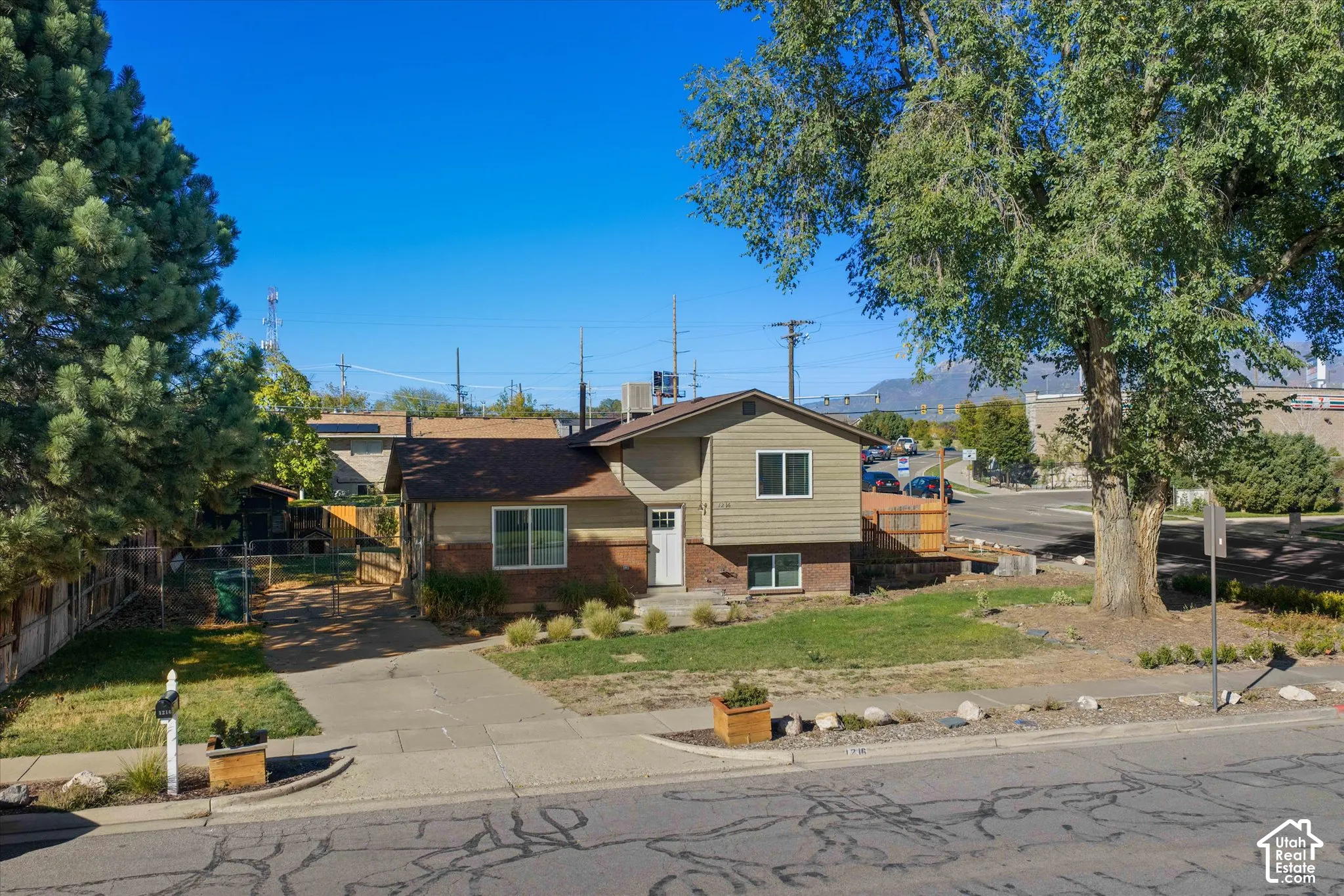Siding and brick exterior with a front entry, concrete driveway, front yard, and mature landscaping