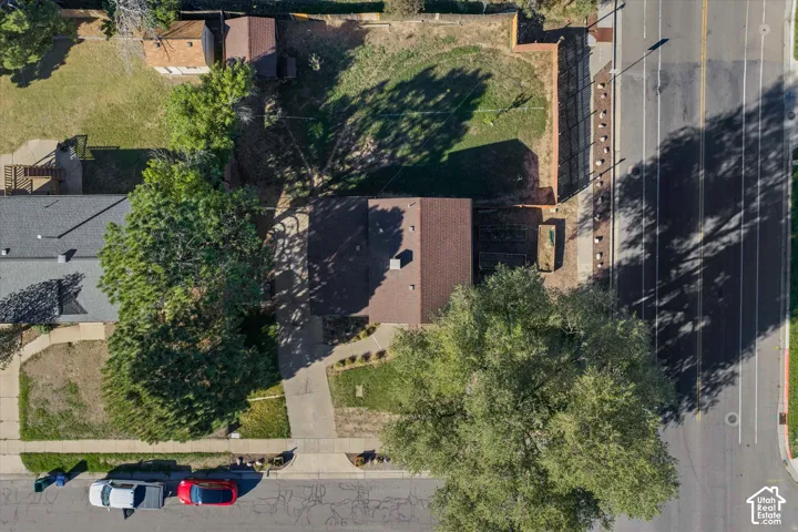 Property with a brown shingle roof, a paved driveway, and established trees