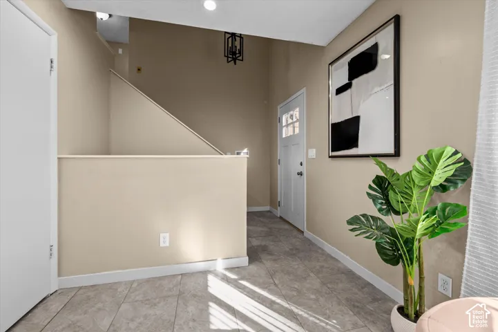Modern entryway featuring neutral-toned walls, tile flooring, recessed ceiling lighting, and contemporary black-framed artwork
