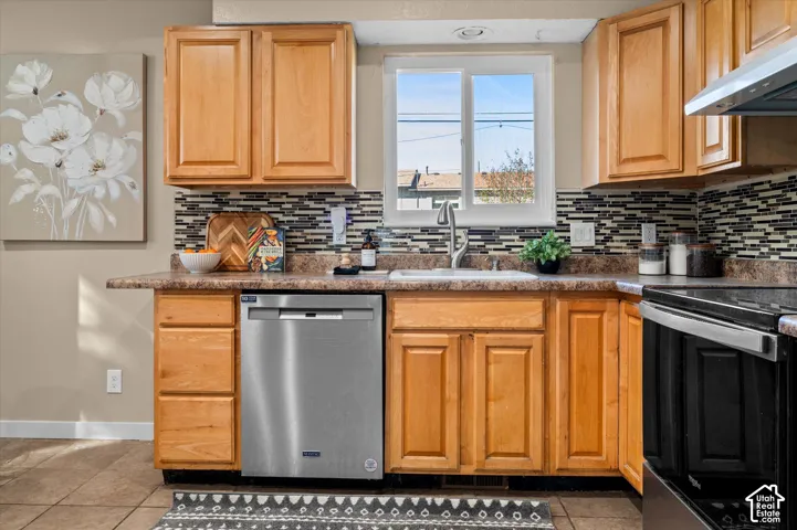 Warm wood cabinetry throughout this kitchen features stainless steel appliances, including a dishwasher and range