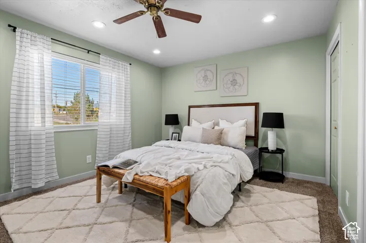 Recessed ceiling lighting, ceiling fan, carpet flooring, a white window frame, and a white interior door