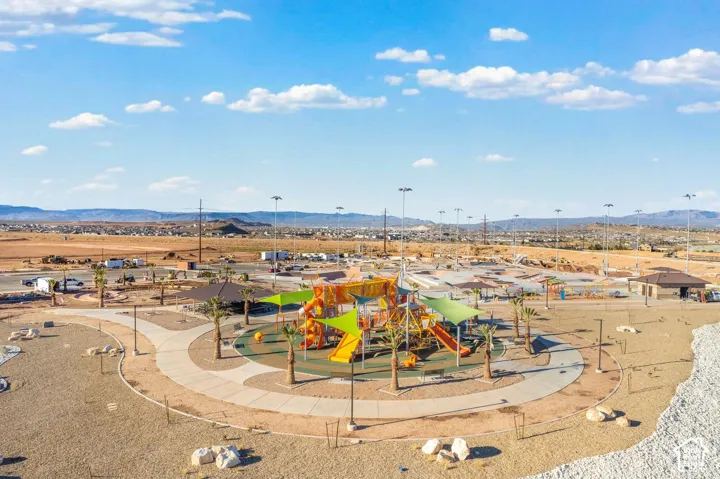 Community playground with multiple play structures, shaded areas, surrounding pathways, and abundant open space