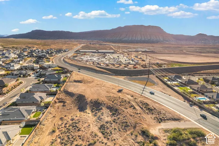 Expansive land parcel featuring desert terrain, visible roadways, surrounding residential developments, and a prominent mountain backdrop
