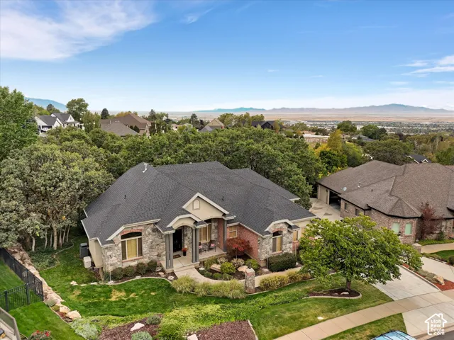 Stone and brick exterior with a multi-level roofline, extensive landscaping, and a paved driveway
