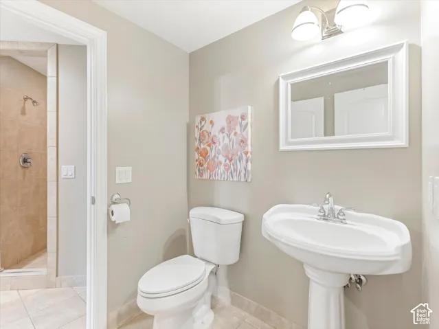 Pedestal sink with chrome faucet, a framed mirror, and a wall-mounted light fixture