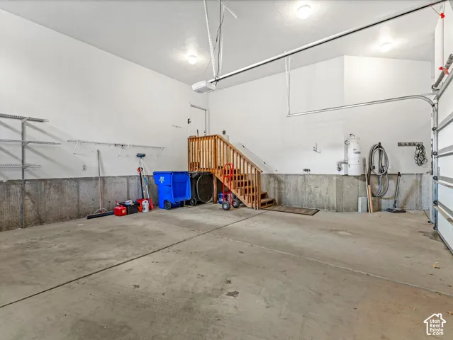 Concrete flooring garage with built-in wooden staircase and wall-mounted shelving
