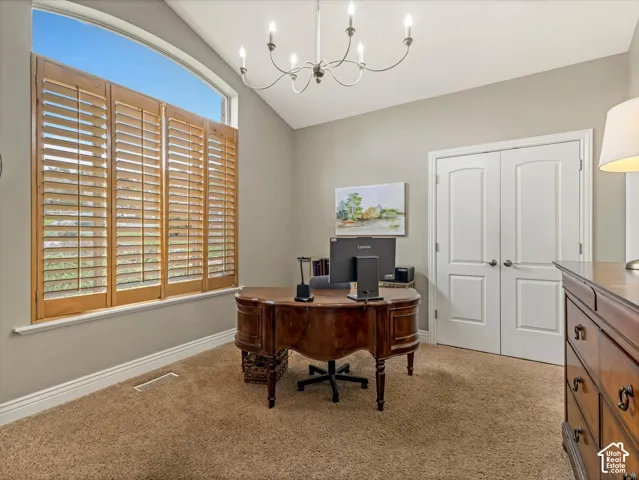 Arched window with wood shutters, vaulted ceiling, built-in chandelier, and carpet flooring
