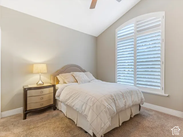 Arched window with plantation shutters, vaulted ceiling, and carpeted flooring