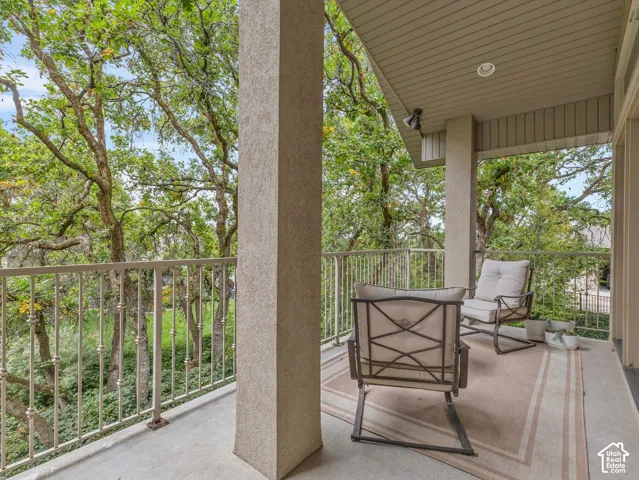 Covered balcony featuring a textured concrete floor, light-colored railing, and overhead recessed lighting