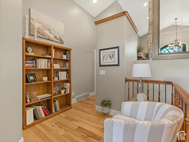 Vaulted ceiling, wood-finish flooring, built-in shelving, wood railing with iron balusters, and recessed lighting